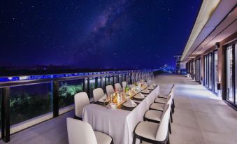 A large table and chairs are set up on the terrace, providing a nighttime ocean view at WING HOTEL
