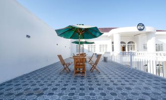 a courtyard with a table and chairs set up for outdoor dining , surrounded by white buildings at Griya RW Family Guest House Redpartner
