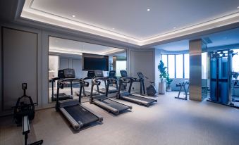 A spacious room with multiple pieces of furniture and an exercise machine positioned in the center on one side at Mercure Guangzhou Beijing Road Pedestrian Street Hotel