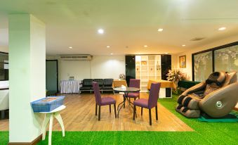 a spacious living room with green carpet , purple chairs , and a dining table set for a meal at Grand Ratchapruek Hotel