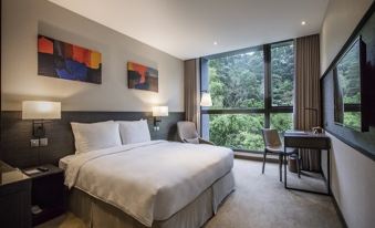 a large bed with white sheets is in a room with a desk , chair , and window at Platinum Hotel
