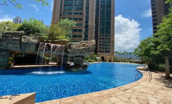 The swimming pool in front is adorned with blue water, while tall buildings stand behind it at Rambler Oasis Hotel