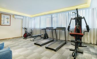 A spacious room contains multiple exercise machines, including an indoor treadmill positioned in the center at Century Garden Hotel