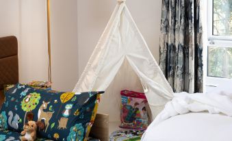 a child 's bedroom with a teepee tent in the corner , surrounded by various toys and books at Hilton Cobham