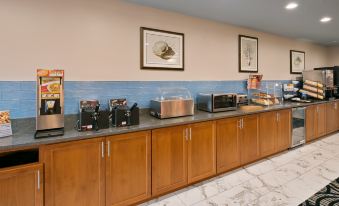 a kitchen counter with various appliances and a blue wall , featuring coffee makers and toaster at Lighthouse Suites Inn