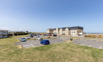 a parking lot filled with cars , with a building in the background and a clear blue sky at The Beaches Hotel