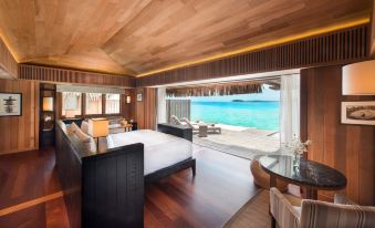 a spacious bedroom with a king - sized bed , a large window , and a view of the ocean at Conrad Bora Bora Nui