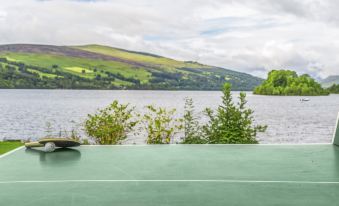 a large green surface is visible in front of a body of water , with mountains in the background at The Kenmore Club