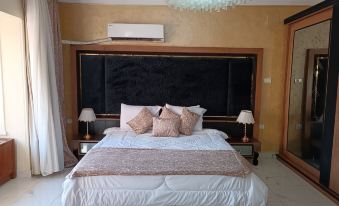 a large bed with a black headboard and white bedding is in a bedroom with a chandelier at Indiana Hotel