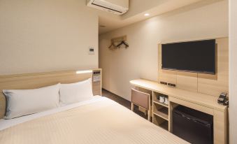 A bedroom with a double bed and a large flat-screen TV mounted on the wall above it at Sotetsu Fresa Inn Osaka Namba