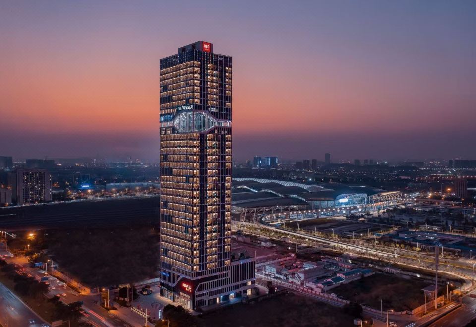A tall, illuminated building in the city at night, viewed from a distance at Radisson RED Guang Zhou South Railway Station