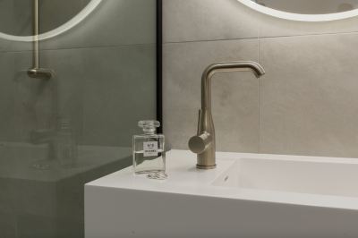 a modern bathroom with a sink , mirror , and faucet , as well as a bottle of liquid soap at Oval Hotel at Adelaide Oval, an EVT hotel