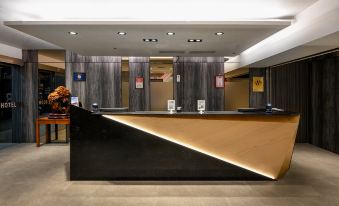 a modern hotel lobby with a black and brown reception desk , multiple chairs , and a television at Le Room Hotel Taoyuan