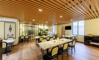 The restaurant's dining room features wood paneling on the ceiling, along with tables and chairs at Hejing Hotel (Futian Exhibition Center, Shenzhen)