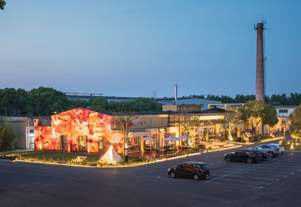 At night, there is a large building with numerous lights on its side, located next to an outdoor area at Ramada Encore by Wyndham Shanghai Pudong Airport