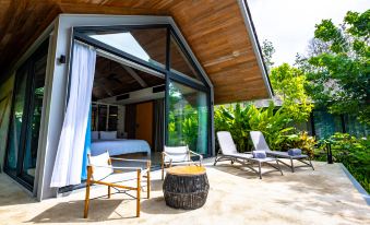 a modern outdoor living space with a wooden deck , lounge chairs , and a pool , surrounded by lush greenery at Island Escape Burasari