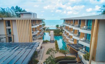 a modern apartment building with multiple balconies and large windows , surrounded by a lush green courtyard at Sand Dunes Chaolao Beach Resort
