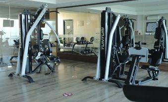 a gym with various exercise equipment , including a weight machine and cardio machines , in a spacious room at Best Western Premier la Grande Hotel