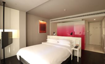 A bedroom with white walls and red accents, including a bed positioned in front at Jinjiang Metropolo Classiq Jing'An Hotel