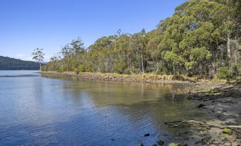 a serene landscape of a river flowing through a wooded area with clear blue skies above at The Fox and Hounds Historic Hotel