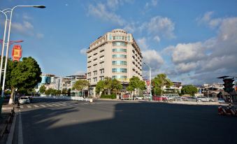 a large , beige - colored building with a curved facade and several other buildings in the background at Diamond Hotel (Liancheng Guanzhishan Airport)