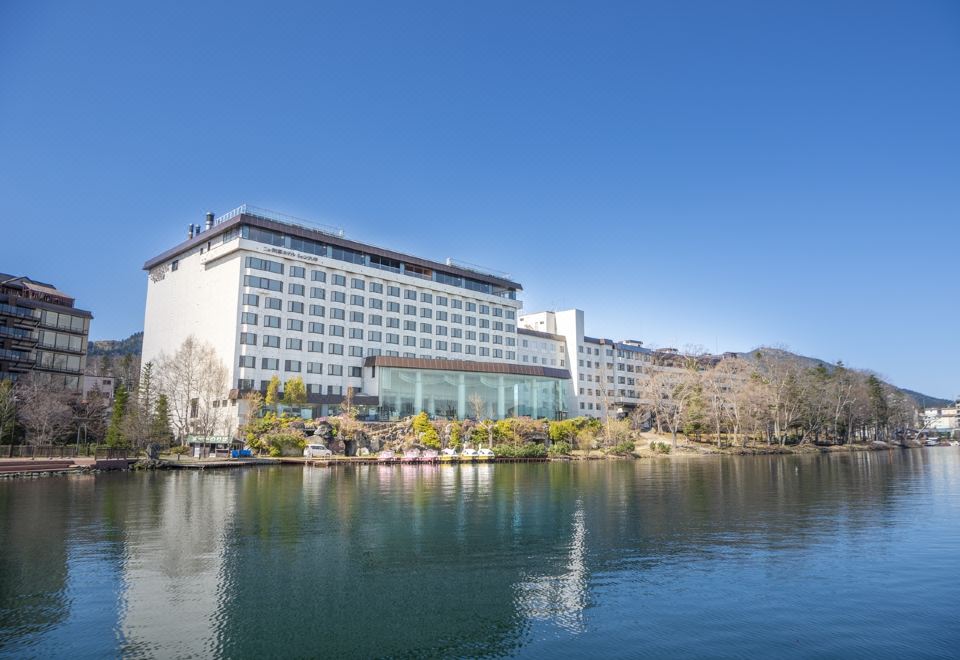 a large white building surrounded by a body of water , with trees in the background at New Akan Hotel