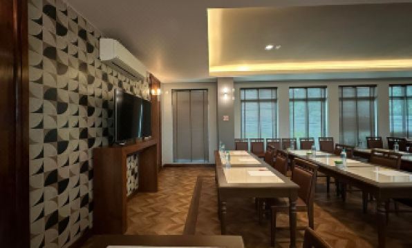 a conference room with a long wooden table , chairs , and a tv mounted on the wall at The Mangrove Hotel