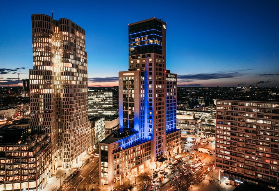 a cityscape with tall buildings lit up at night , creating a vibrant atmosphere and creating a contrasting atmosphere at Waldorf Astoria Berlin