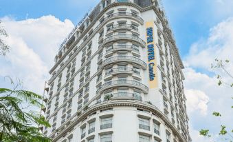 a tall , white building with a blue sign on top is surrounded by trees and bushes at Super Hotel Candle