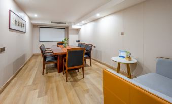 There is a conference room with a wooden table and chairs in the center, facing an office with a desk and computer at Hongge Apartment Hotel