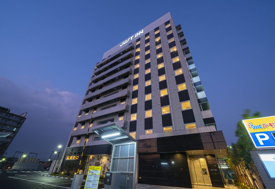 a modern building with a large sign on the top and another sign in front at Just Inn Matsusaka Station