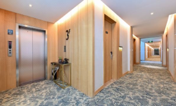 There is a large room with wood paneling and an elevator in the middle on one side at Atour X Hotel Beijing Sanlitun Taikoo Li