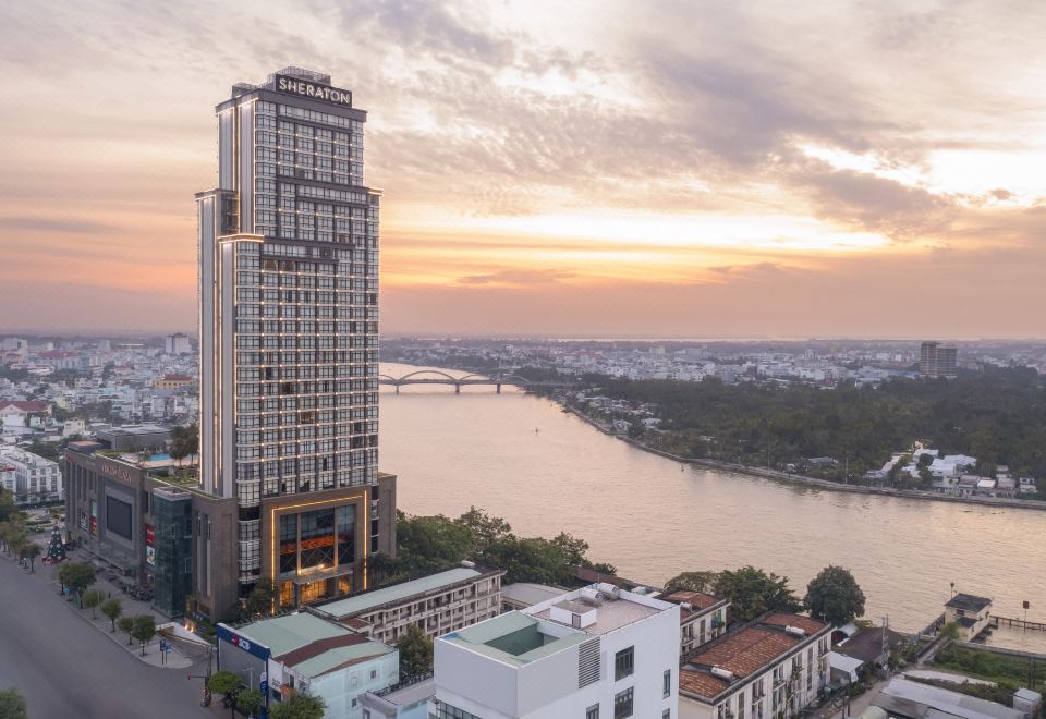 a city skyline with a tall building in the foreground , surrounded by other buildings and a river at Sheraton Can Tho