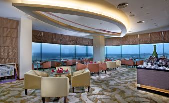 a large , modern restaurant with high ceilings and curved windows offers a view of the ocean at Grand Artos Hotel & Convention
