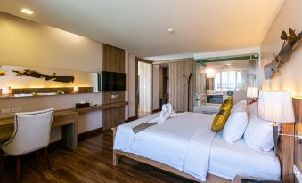 a modern hotel room with a large bed , white linens , and wooden flooring , along with a kitchenette area at Grand Ratchapruek Hotel