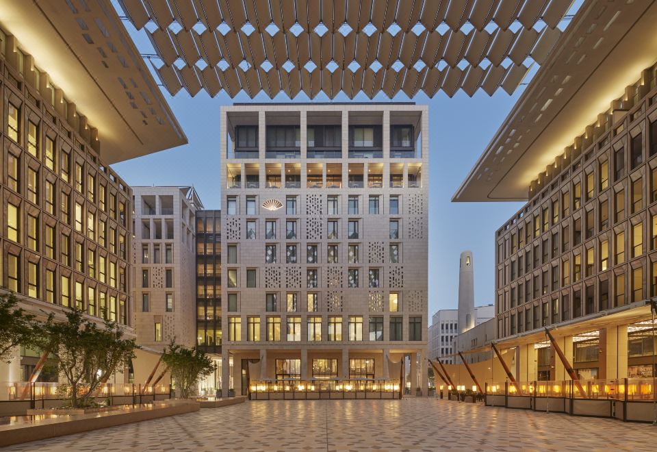 a modern building with a large atrium and multiple floors , surrounded by palm trees and lit up at night at Mandarin Oriental, Doha