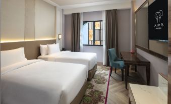 The bedroom features double beds and a desk in the middle, with an open door beside it at Aira Hotel Bangkok Sukhumvit 11