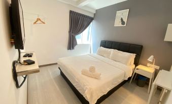 a clean and well - organized bedroom with a white bed , a black couch , and a tv at Havona Hotel @ Taman Tropika Kulai - Self Check-In