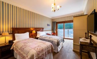 a hotel room with two beds , one on the left and one on the right side of the room at The Whispering Pine Lodge