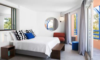 a modern bedroom with a white bed , blue and black pillows , and a round mirror on the wall at Salt of Palmar, Mauritius