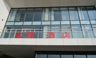 a building with a red sign on the balcony , indicating that it is a restaurant at Dongji Island Dongguan Hotel