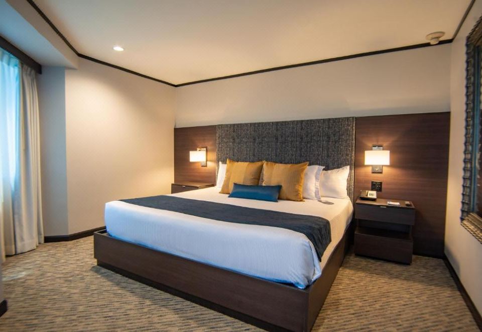 a large bed with a wooden headboard and two lamps on either side is shown in a hotel room at Grand Hotel Tijuana