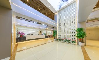 A large lobby with ceiling lights and plants, accompanied by an entryway at Capital Airport International Hotel