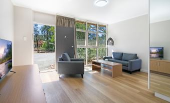 a modern living room with hardwood floors , a gray couch , and a large window overlooking the outdoors at Discovery Resorts - Wilpena Pound