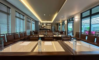 a conference room with wooden tables and chairs , water bottles on the table , and large windows at The Mangrove Hotel