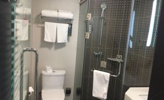 a modern bathroom with a toilet , sink , and shower area , along with towels and other accessories at Ibis Hotel