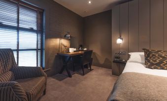 a modern hotel room with a bed , desk , and chair , as well as a window and curtains at Dakota Edinburgh