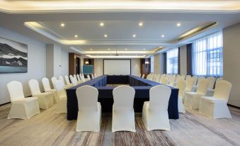 a large room arranged with long tables and chairs facing the front for an event at Zhedong Chuyue International Hotel