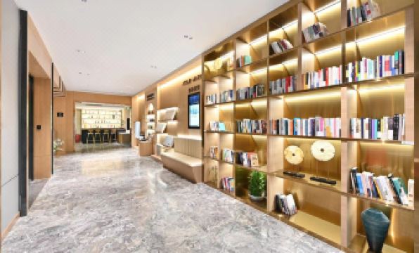 There is a spacious room with bookshelves and seating for two people on one side of the wall at Atour X Hotel Beijing Sanlitun Taikoo Li