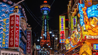 通天閣(Tsutenkaku)是位於日本大阪市浪速區新世界商圈的知名瞭望塔與地標,被譽為「浪速的艾菲爾鐵塔」。塔高103公尺,最初建於1912年,目前的建築為1956年重建的第二代塔身,已被列為日本的「登錄有形文化財」。
核心看點與驚險體驗黃金展望台與比利кен(Billiken)福神:位於高空的展望台可以360度飽覽大阪市景,這裡供奉著著名的「摸腳底就能帶來好運」的比利肯神像。TIP THE TSUTENKAKU:高達93公尺的懸空玻璃地板展望台,提供驚險的空中俯瞰視角。TOWER SLIDER(巨型溜滑梯):從地上22公尺高處沿著電梯塔外側一路螺旋下滑至地下1階,全長60公尺僅需約10秒,滑行時還能透過透明頂棚仰望塔身。DIVE & WALK:在地上26公尺高處進行高空繩索漫步,以及從40公尺高處一躍而下的極限心跳體驗。地下 WAKUWAKU 樂園:聚集了江崎格力高(Glico)、森永製菓、日清食品等日本知名食品大廠的限定商品販售區。
參觀資訊營業時間:每日 9:00~21:45(一般展望台最晚入場時間為 21:15)。標準門票:大人(高校生以上)約 1,200~1,500 日圓,兒童(5歲~中學生)約 400~600 日圓(部分刺激設施如溜滑梯需額外收費)。持大阪周遊卡或大阪樂遊券可享一般展望台免費入場。貼心提醒:通天閣目前已實施入場時間預約制,建議提前至通天閣預約網站訂票以節省現場排隊時間。
#日本 #大阪 #通天閣
